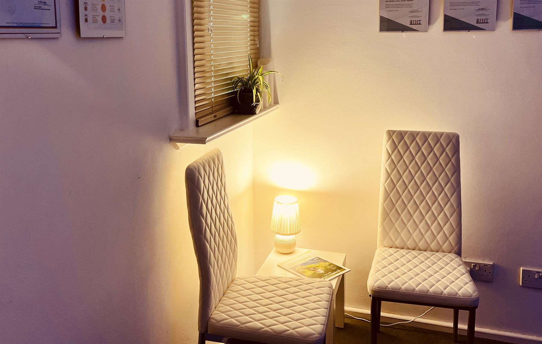 The quiet waiting area with two chairs and a table lamp at Leafield Hub