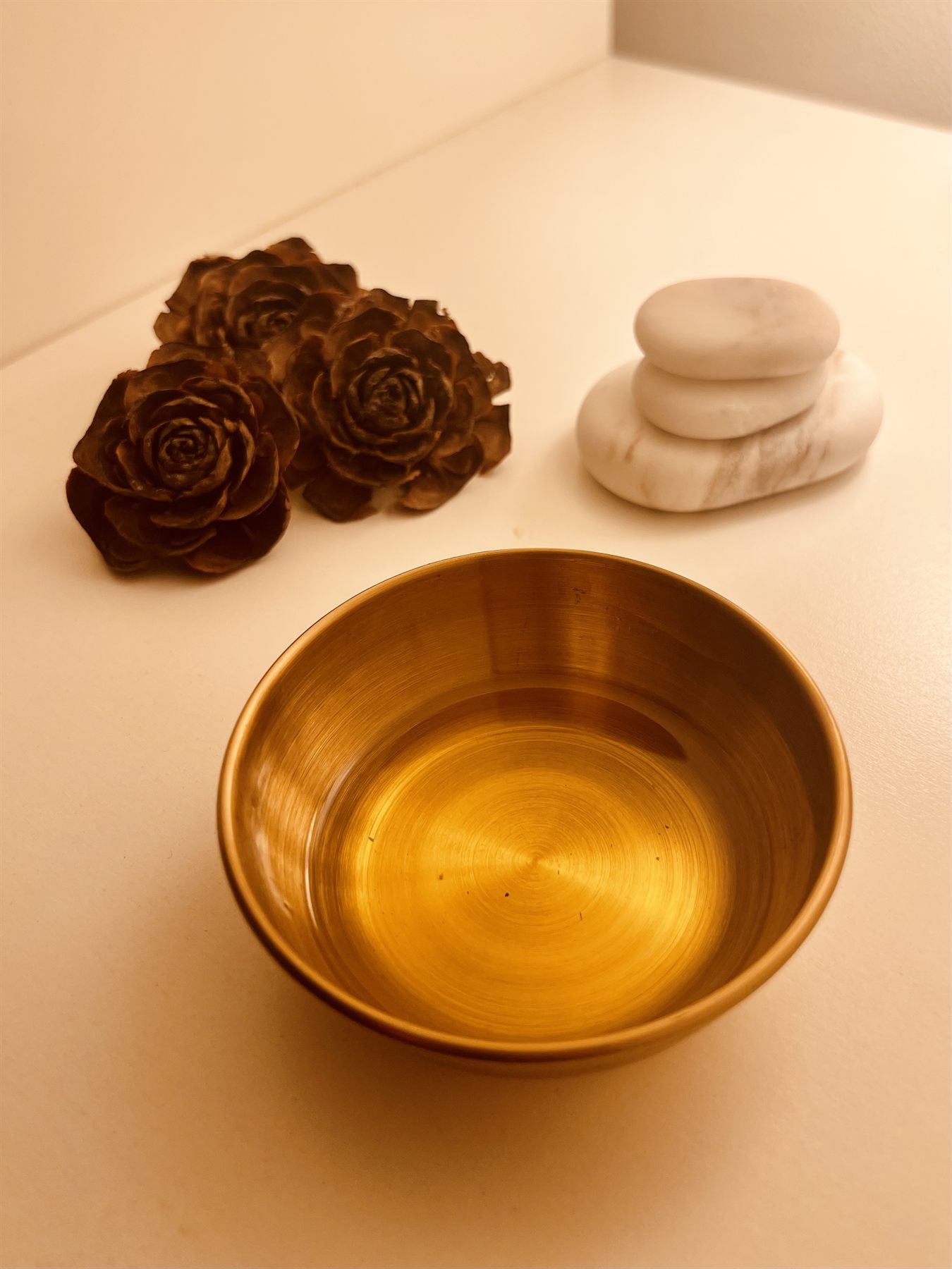 Polished marble massage stones and a brass oil bowl in the treatment room