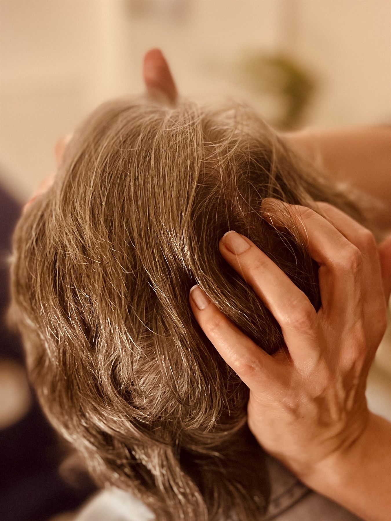 Close view of fingers working through the hair during a scalp massage